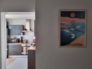 A modern kitchen with grey cabinets, a wooden countertop, and a red kettle. - Les Cognassiers (Agen)