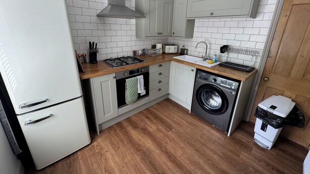 A compact kitchen with a white refrigerator, a gas stove, a built-in oven, a washing machine, and a sink. - 18 The Wharfage (Telford)
