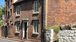 A traditional brick building with a prominent entrance, a visible street sign indicating a 20 zone, and a stone wall adjacent to the building. - 18 The Wharfage (Telford)