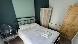 A bedroom with a bed, a chair, a wardrobe, and a door. - 18 The Wharfage (Telford)