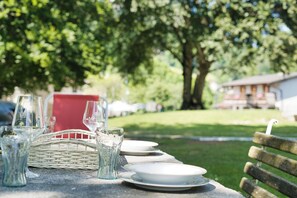 A table set outdoors with clear glassware and plates, a wicker basket, and a bench. - Rustico nel parco - Two Bedroom Apartment, Sleeps 4 (Piani Resinelli II)