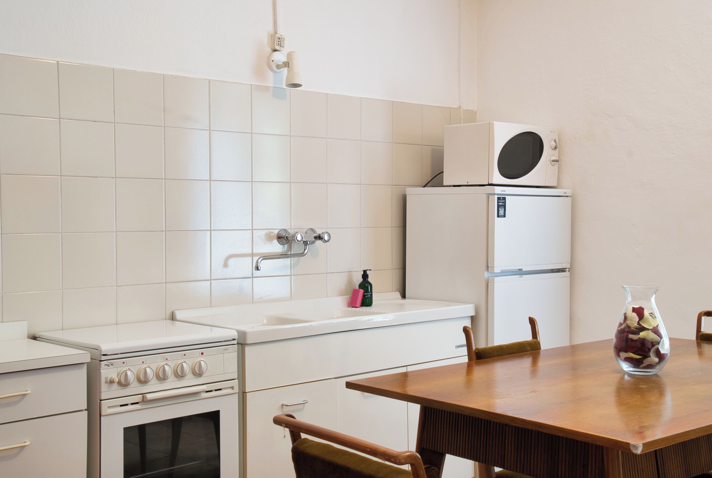 Une cuisine avec des appareils électroménagers blancs, un évier et une table à manger avec des chaises.