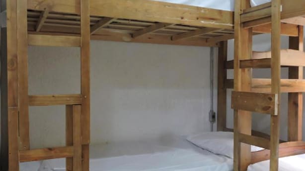 A bunk bed with a wooden frame and white bedding. - Olah Hostel Paulista (São Paulo)