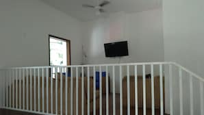 A room with a white ceiling fan, a television mounted on the wall, and a window with a view of greenery outside. - Olah Hostel Paulista (São Paulo)