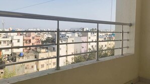 A balcony with a metal railing overlooking a residential area with various buildings. - 1BHK Comfy Stay 202 (Pune)