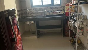A kitchen with a refrigerator, a sink, and a dish rack. - 1BHK Comfy Stay 202 (Pune)