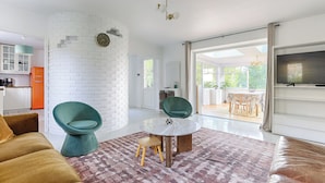 A modern living room with a white brick wall, a round coffee table, and a large TV.