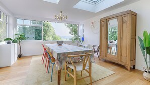 A dining area with a table, chairs, a chandelier, and a large wooden cabinet.