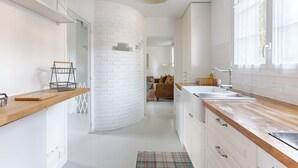 A modern kitchen with white brick walls, wooden countertops, and a central island.