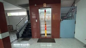 Un ascensor con una franja roja y amarilla, una puerta azul y una escalera de metal.