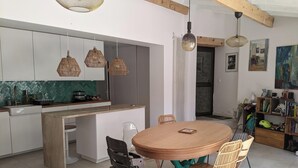 A modern kitchen with a central island, pendant lights, and a dining area with a round table and chairs. - Villa with swimming pool and garden. (Marseille)