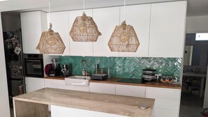 A modern kitchen with white cabinets, a green backsplash, and three woven pendant lights. - Villa with swimming pool and garden. (Marseille)