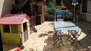 A patio with a table and chairs, a small playhouse, and a blue play structure. - Villa with swimming pool and garden. (Marseille)