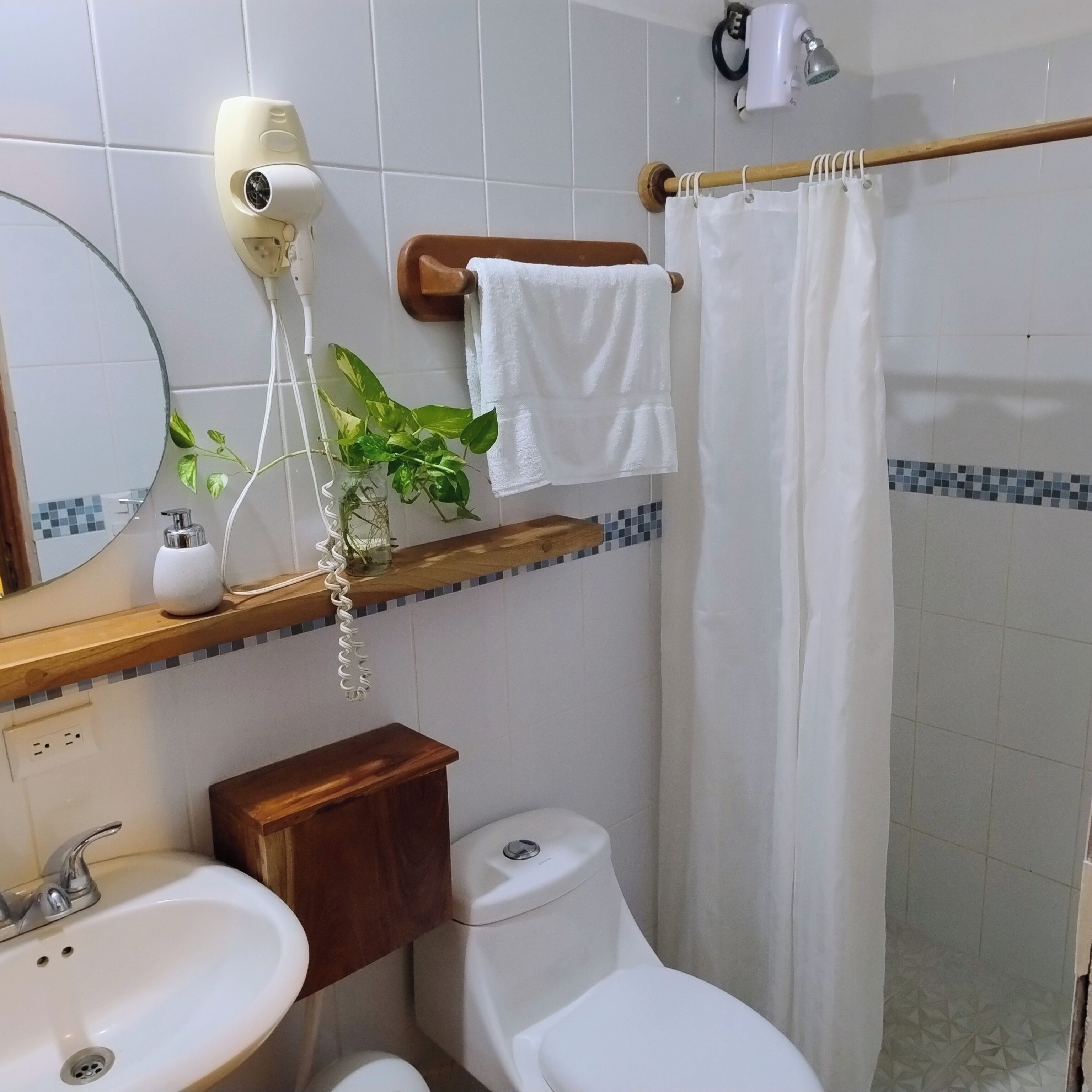 Un baño con lavabo, inodoro y secador de pelo montado en la pared.