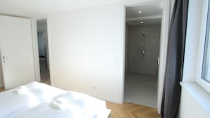 A hotel room with a bed, a shower area, and a window with curtains. - Margot (Vienna)