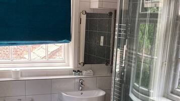 A bathroom with a glass-enclosed shower, a sink, and a toilet.