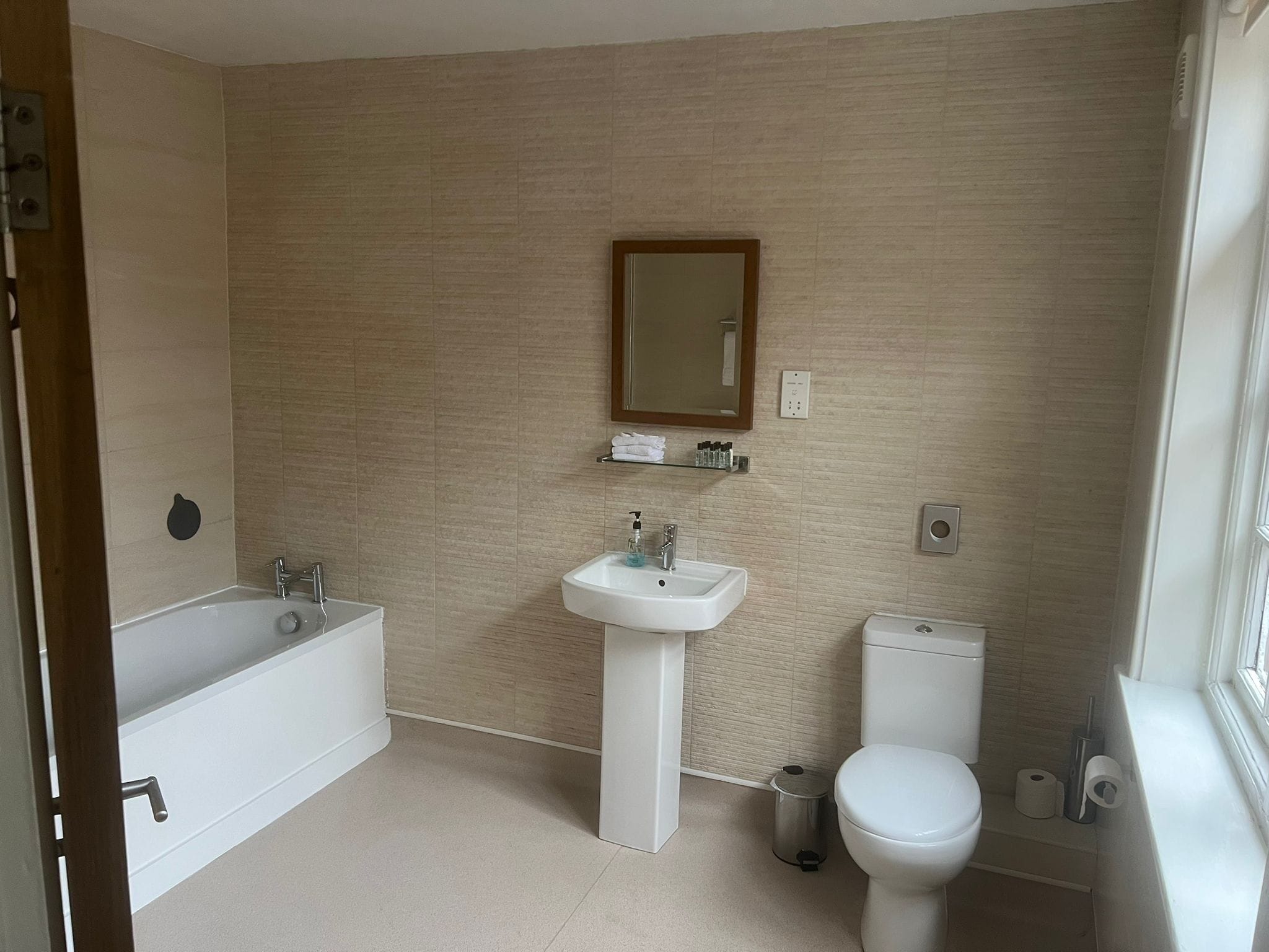 A bathroom with a bathtub, sink, toilet, and a mirror on the wall.