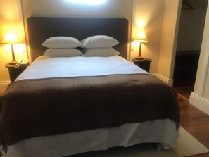 Ein ordentlich bezogenes Bett mit einer dunkelbraunen Decke, zwei Nachttischlampen und einem Telefon auf dem Nachttisch.