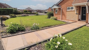 A residential property with a paved driveway, a well-maintained lawn, and a brick house with a black door. - 3 Hawk Place (Whitehaven)