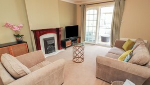 A living room with two sofas, a fireplace, a television, and a sliding glass door leading to an outdoor area. - 3 Hawk Place (Whitehaven)