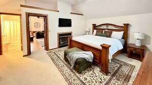 Ein Schlafzimmer mit einem hölzernen Bett, Deckenventilator, Kamin und Fernseher an der Wand.