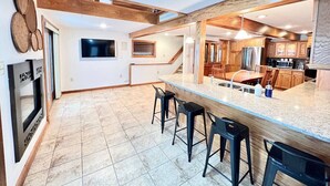 Eine moderne Küche mit einer großen Kochinsel, Barhocker, einem Backofen und einem Fernseher.