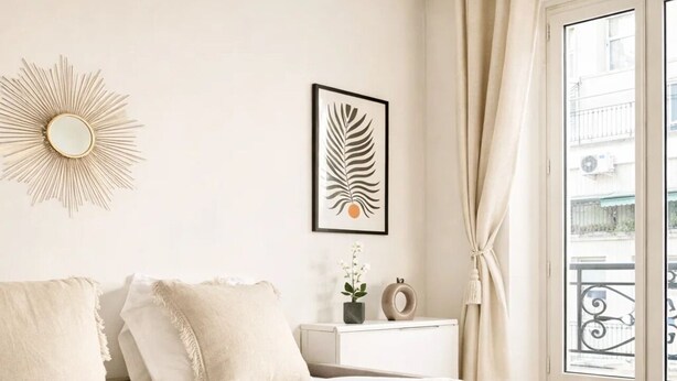 A hotel room with a bed, a nightstand, a framed leaf artwork, and a view of the outside. - 1565 Pétion (Paris)