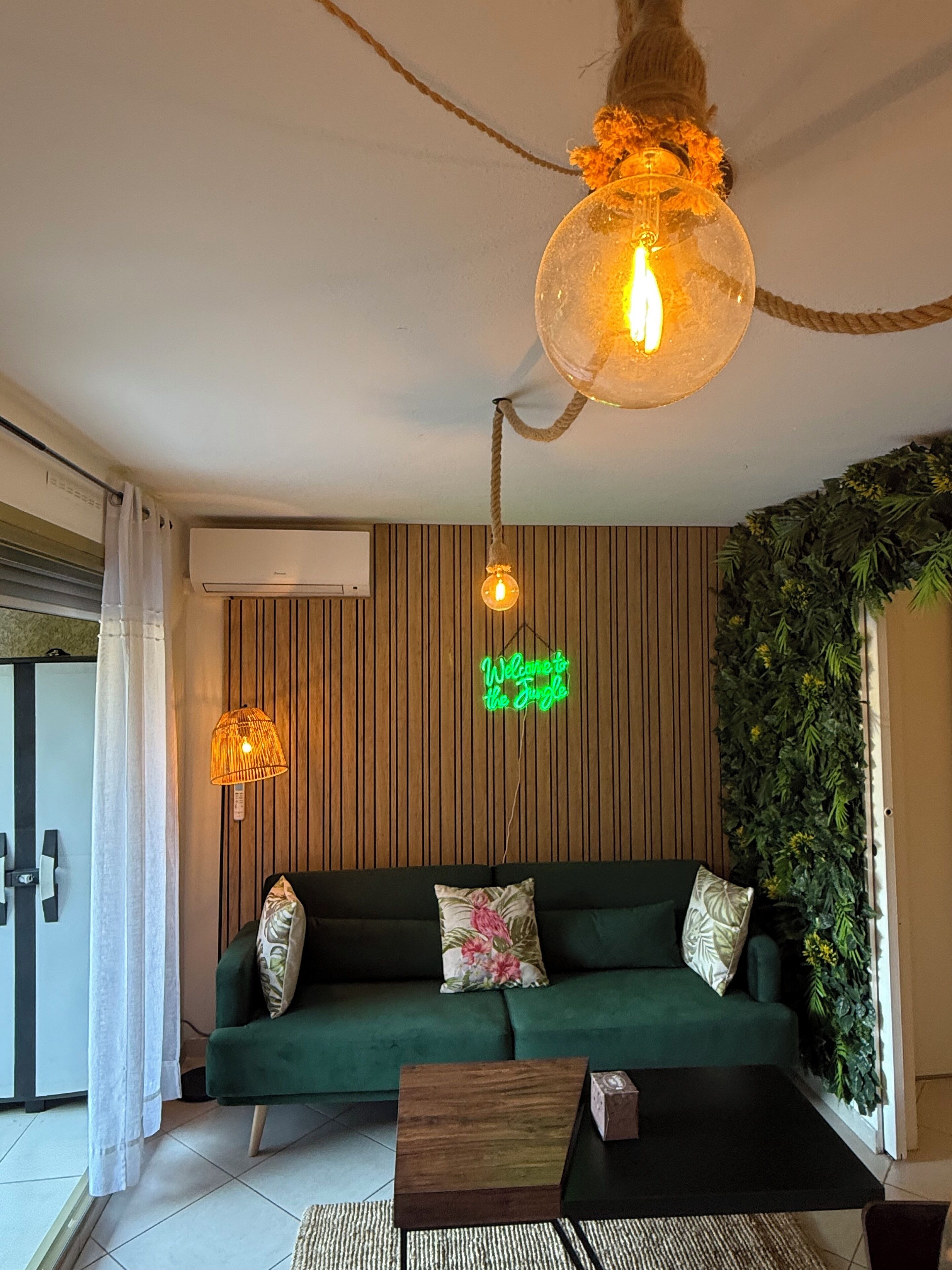 Un soggiorno moderno con un divano verde, un tavolino in legno e una lampada a sospensione.
