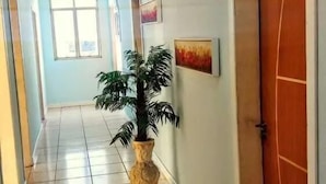 A hallway with tiled flooring, a potted plant, and a door on the right. - DC Hostel (Florianópolis)