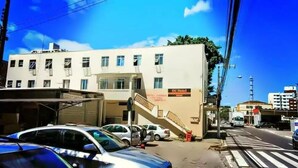 A building with a sign for DC Hotel, a staircase leading to the entrance, and parked cars on the street. - DC Hostel (Florianópolis)