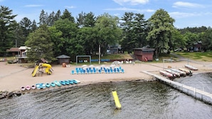 A lakeside resort with a sandy beach, a children's play area, and a dock with boats. - Cabin 1 at Heath's Resort (Pine River)