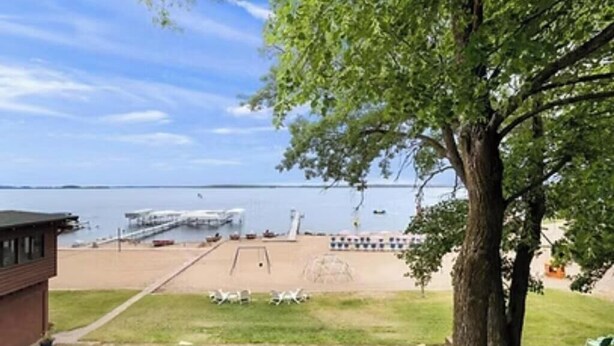 A beach with a swing set, a small building, and a tree. - Cabin 1 at Heath's Resort (Pine River)