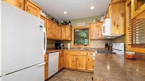 A kitchen with wooden cabinets, a white refrigerator, and a granite countertop. - Cabin 1 at Heath's Resort (Pine River)