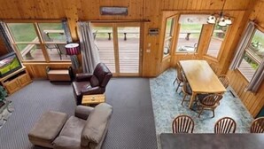 A wooden cabin interior with a sofa, a dining table, and chairs.