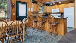 A wooden interior with a dining area, kitchen, and a view of the outdoors.