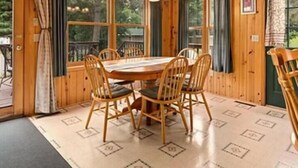 A wooden cabin with a dining area featuring a round table and four chairs. - Cabin 12 at Heath's Resort (Pine River)
