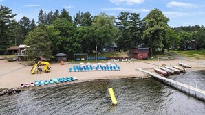 A lakeside resort with a sandy beach, a children's play area, and a dock with boats. - Cabin 12 at Heath's Resort (Pine River)