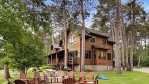 A cabin with a deck, outdoor seating, and a fire pit.