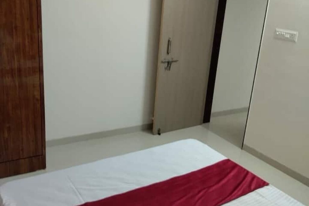 A bedroom with a bed, a wooden wardrobe, and a door with a handle.