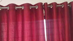 A red curtain with a metallic rod. - 1BHK Cozy Stay 2 (Pune)