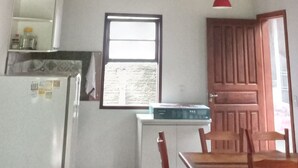 A kitchen with a refrigerator, a window, and a door.
