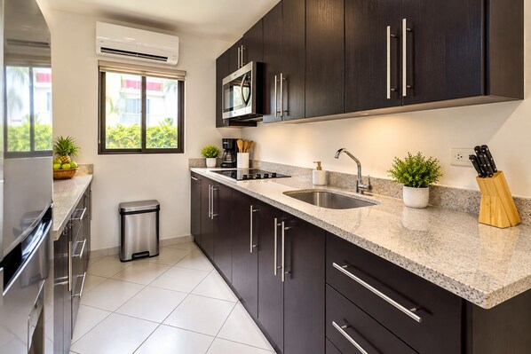 A modern kitchen with dark cabinets, a stainless steel range, a microwave, and a granite countertop.