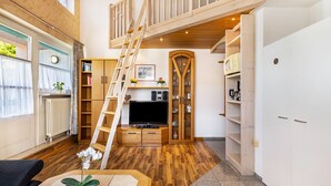 A loft-style room with a wooden staircase, a television, and built-in shelving.