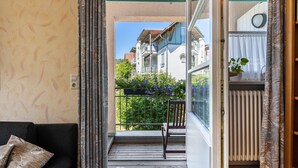A balcony with a chair, a potted plant, and a view of neighboring buildings.