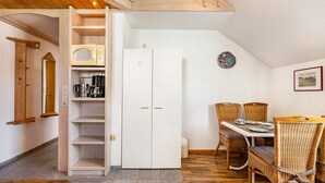 A compact kitchen with a microwave, coffee maker, and open shelving.