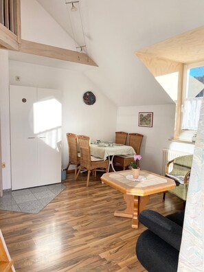 Una habitación con una mesa de comedor, sillas, un sofá, un radiador y una ventana.