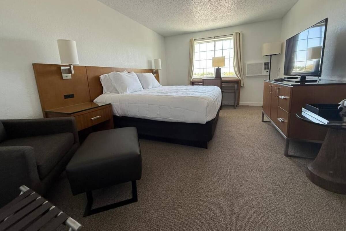 Ett hotellrum med en säng, ett skrivbord, en tv och en stol.