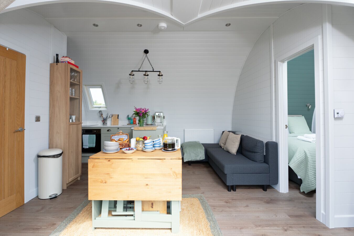 Un espace de vie compact comprenant un coin cuisine, un coin repas, un canapé et un lit.