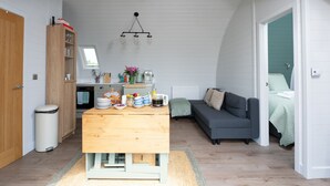 Un espace de vie compact comprenant un coin cuisine, un coin repas, un canapé et un lit.