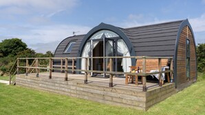 Un bâtiment moderne en forme de dôme, doté d’une terrasse en bois et d’une grande porte vitrée.